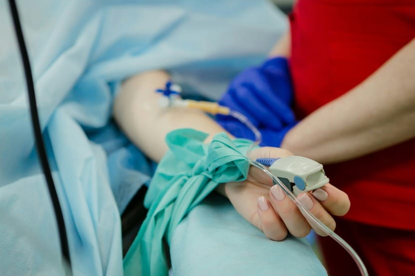 A closeup photo of a hospital patient's hand with an IV connected
